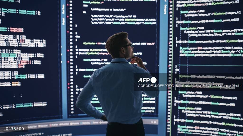 Ingénieur analysant du code sur de grands écrans dans une salle de supervision réseau