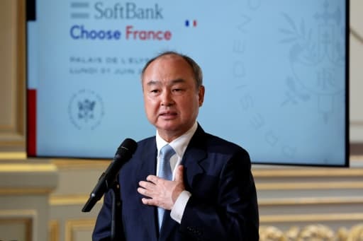 Un homme en costume s'exprime au micro devant un écran SoftBank et Choose France