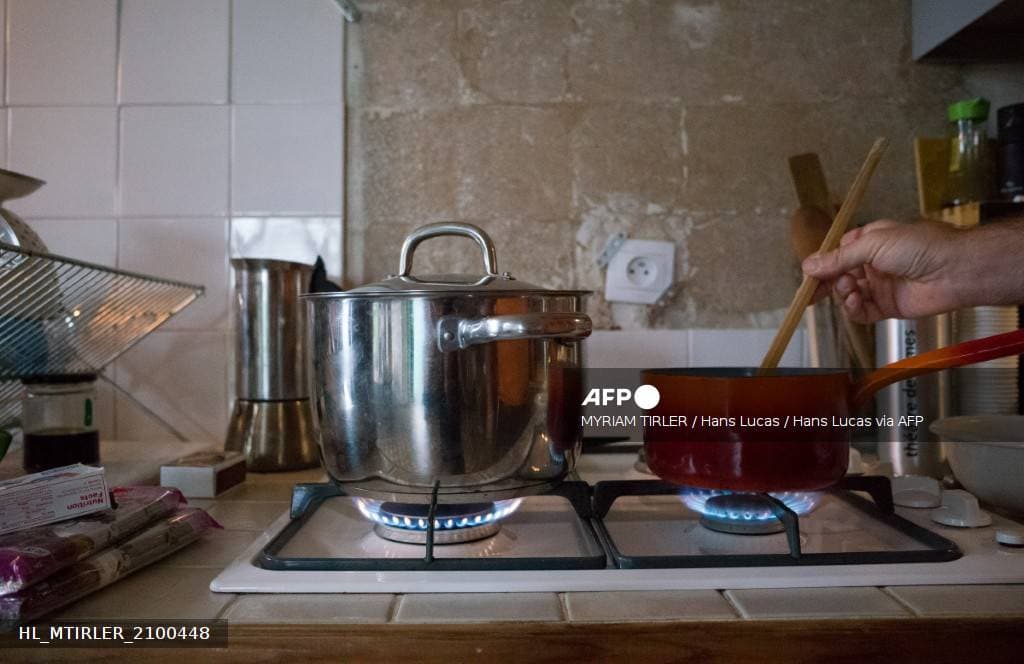 Plaque de cuisson au gaz dans une cuisine française, deux brûleurs allumés sous une casserole inox et une cocotte rouge