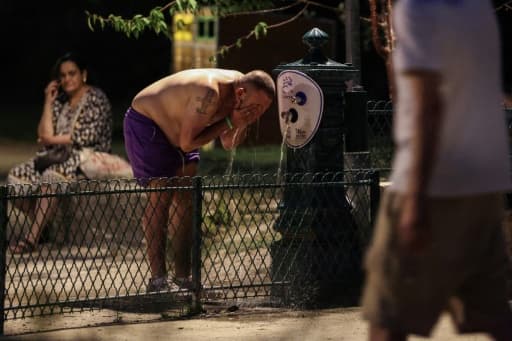 Un homme se rafraîchit à une fontaine à Paris pendant la canicule