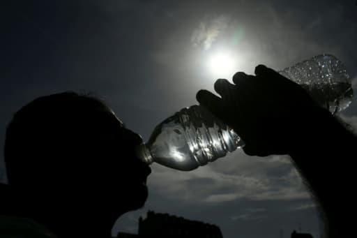 Un homme boit de l'eau en plein soleil pendant la canicule