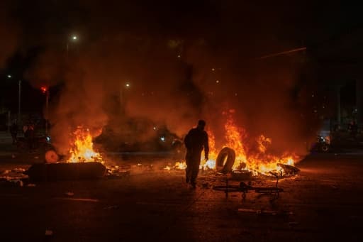 Un manifestant jette un pneu dans un feu lors d'affrontements avec la police à Bogota, en Colombie