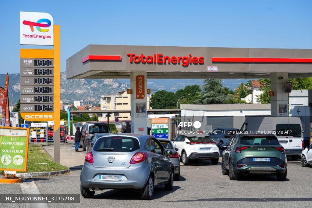Totem de prix d'une station-service TotalEnergies affichant les tarifs des carburants, devant une file de voitures