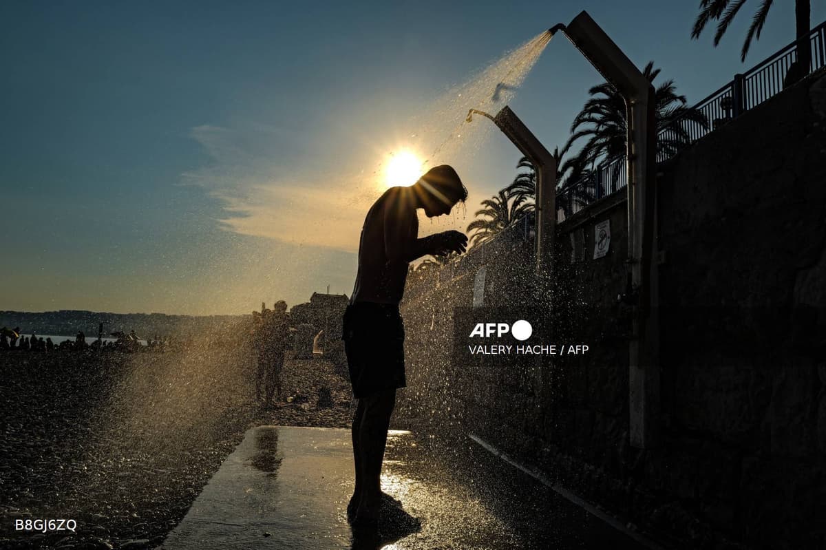 Un homme se rince sous une douche de plage face au soleil, sur le littoral niçois.