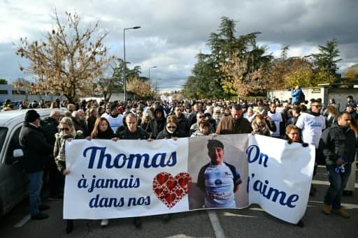 Une marche blanche compacte derrière une banderole portant le portrait de Thomas