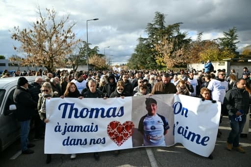 Une marche blanche compacte derrière une banderole portant le portrait de Thomas