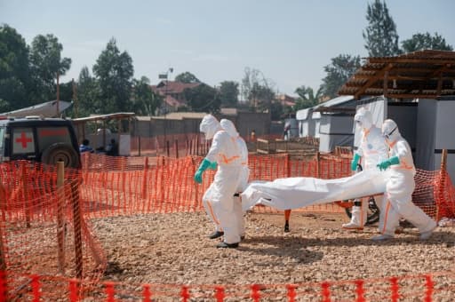 Des agents sanitaires en équipement de protection transportent un corps