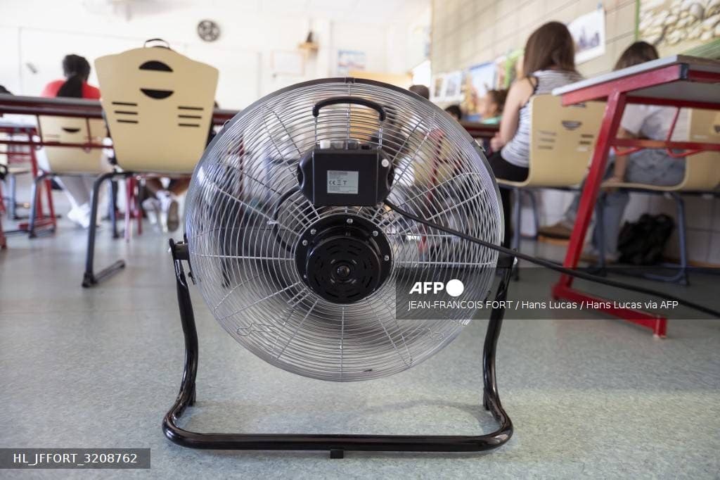 Un grand ventilateur posé au sol souffle dans une salle de classe pendant une vague de chaleur