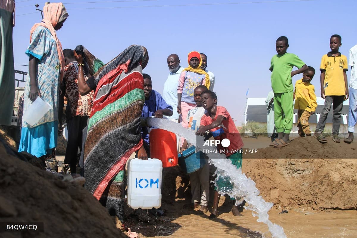 Des familles déplacées par la guerre au Soudan font la queue pour recueillir de l'eau dans un camp.