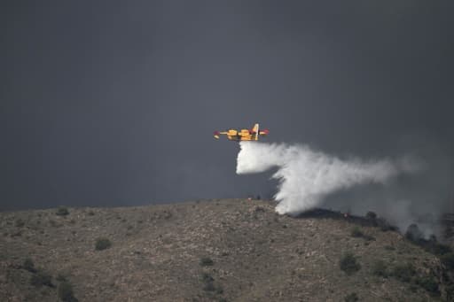 Un Canadair largue de l'eau au-dessus d'une colline en feu, dans un épais nuage de fumée, près de Los Gallardos en Espagne.