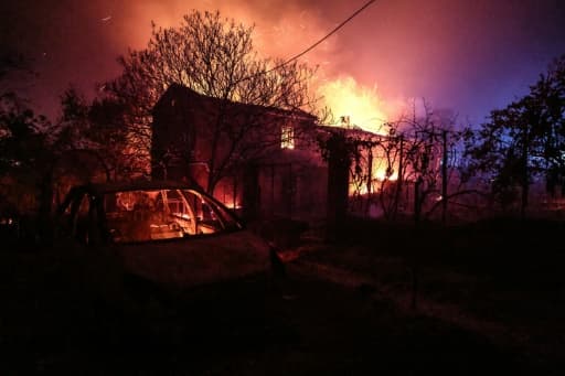 Une maison prise dans les flammes de nuit, une voiture calcinée au premier plan