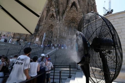 Des touristes se rafraîchissent sous la brume d'un ventilateur devant la Sagrada Família, à Barcelone.