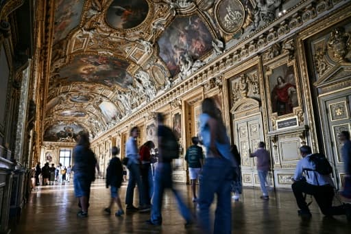Des visiteurs dans la galerie d'Apollon du Louvre sous ses plafonds peints