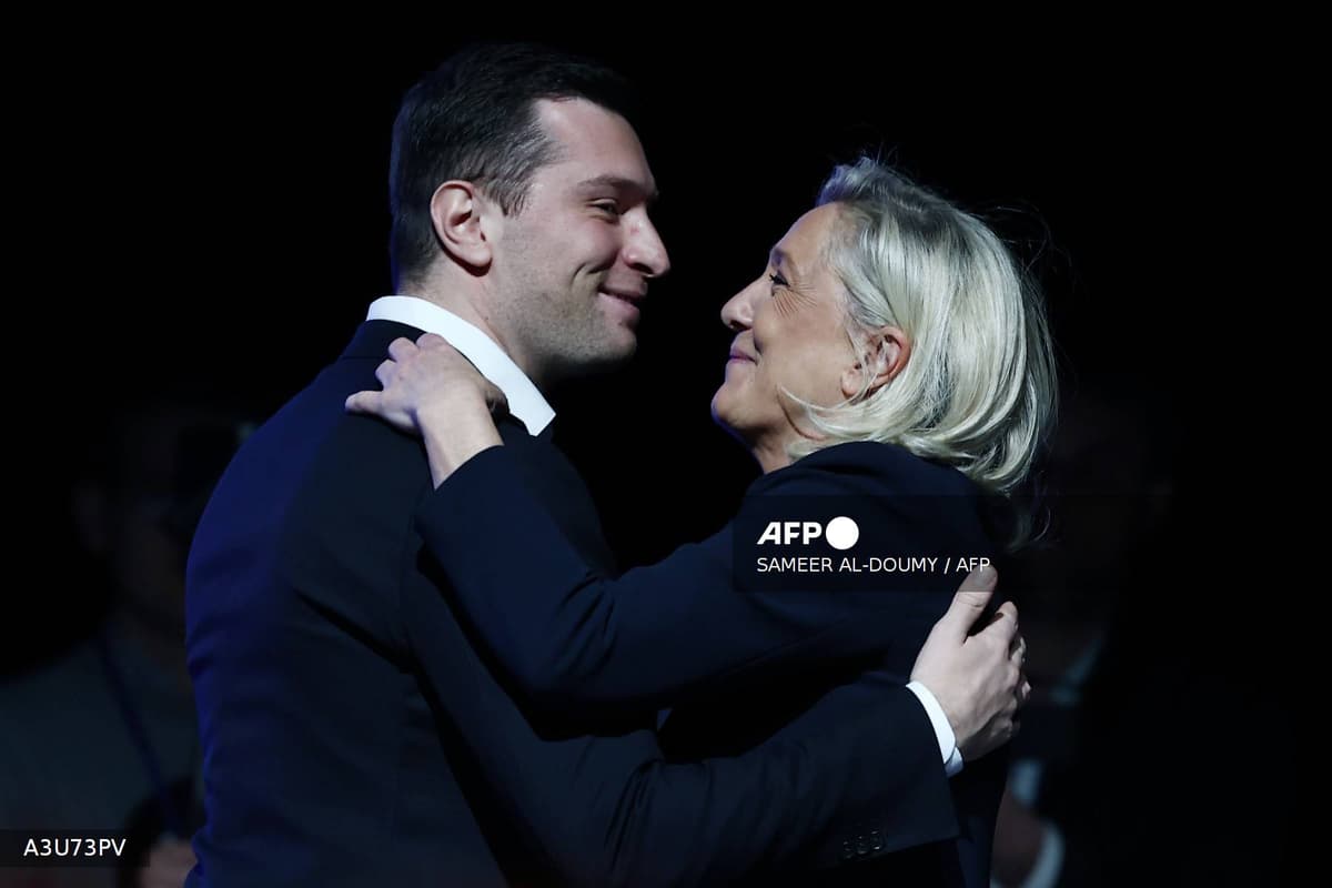 Jordan Bardella et Marine Le Pen s'enlacent sur scene lors d'un meeting du Rassemblement national.