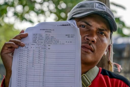 Akhmad, ancien membre d'équipage d'un navire de pêche chinois, montre son contrat en Indonésie