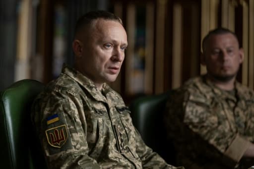 Mykhaïlo Drapaty en uniforme, assis, écusson ukrainien sur l'épaule