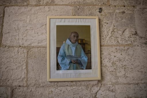 Portrait encadré du père Jacques Hamel accroché au mur de pierre de son église