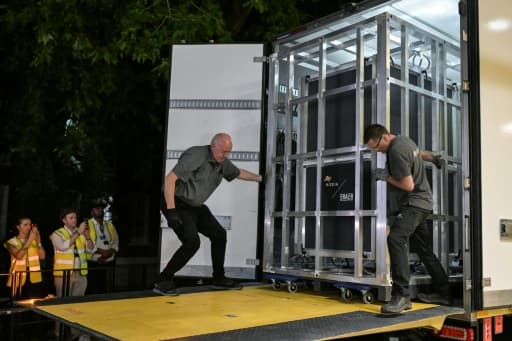 De nuit, des manutentionnaires déchargent une caisse métallique d'un camion devant le British Museum.