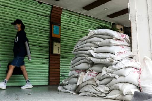 Sacs de sable empilés devant le rideau baissé d'un commerce à Taipei avant l'arrivée du typhon Bavi.