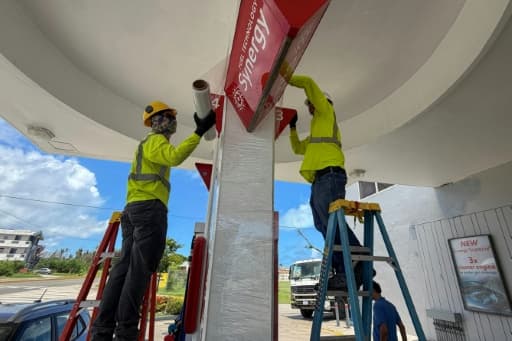 Ouvriers consolidant les panneaux d'une station-service avant l'arrivée d'un super typhon à Saipan