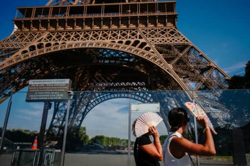 Deux touristes s'éventent devant la tour Eiffel en pleine canicule