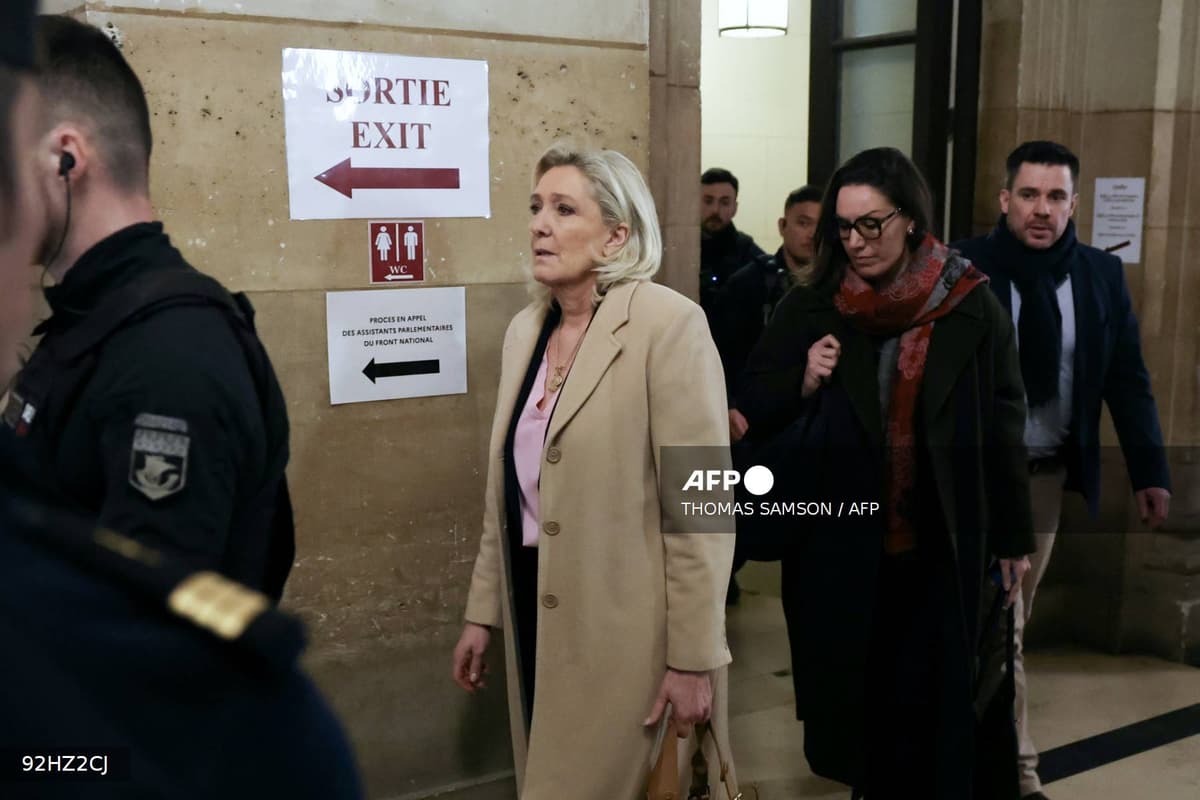 Marine Le Pen au palais de justice de Paris devant un panneau indiquant le procès en appel