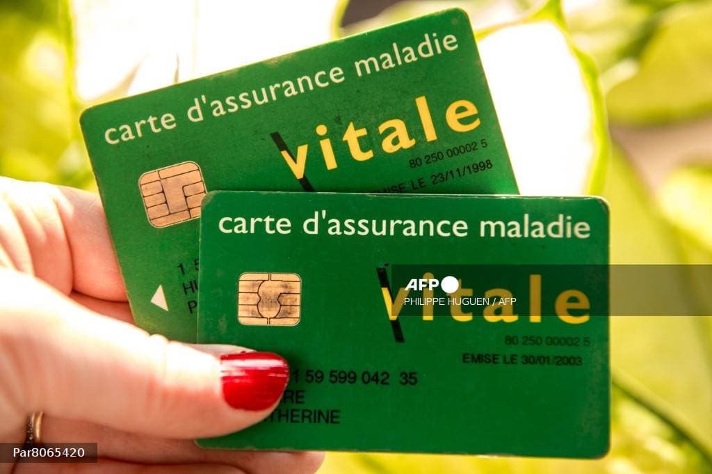 Une main tient deux cartes d'assurance maladie