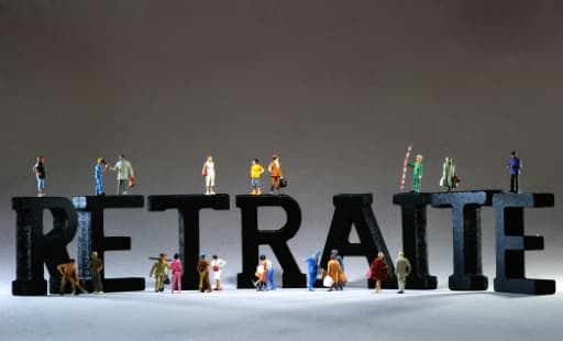 Des figurines de personnages posées sur et devant les lettres noires du mot retraite