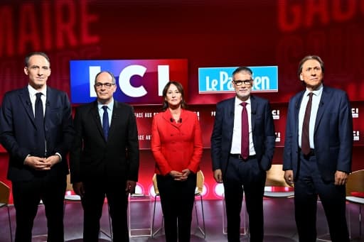 Cinq candidats debout sur un plateau de télévision, devant un décor rouge