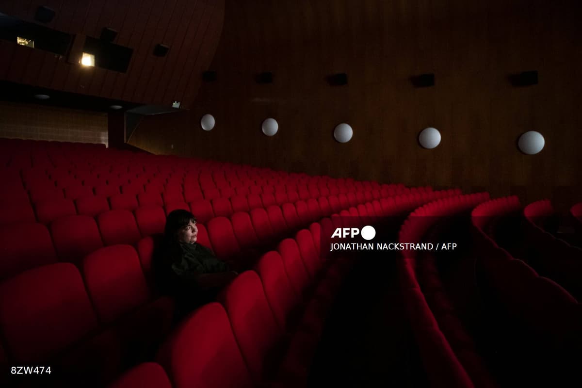 Une spectatrice seule dans une salle de cinéma vide aux fauteuils rouges