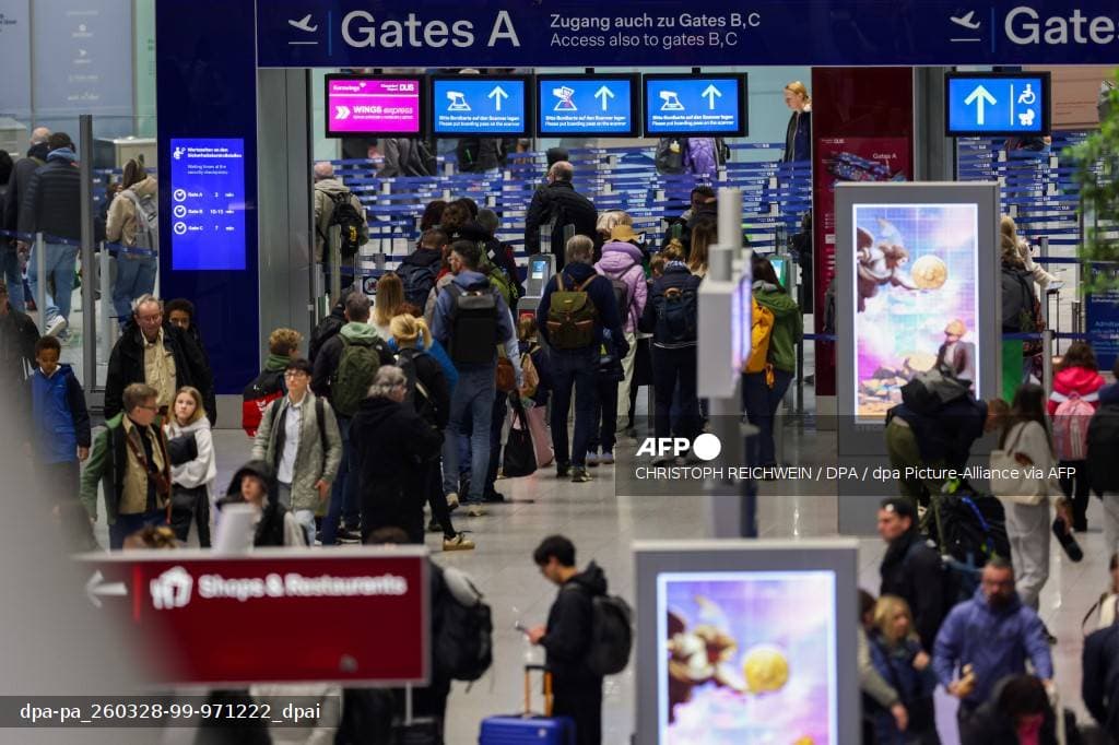 Voyageurs dans le hall de départ d'un aéroport devant les panneaux des gates