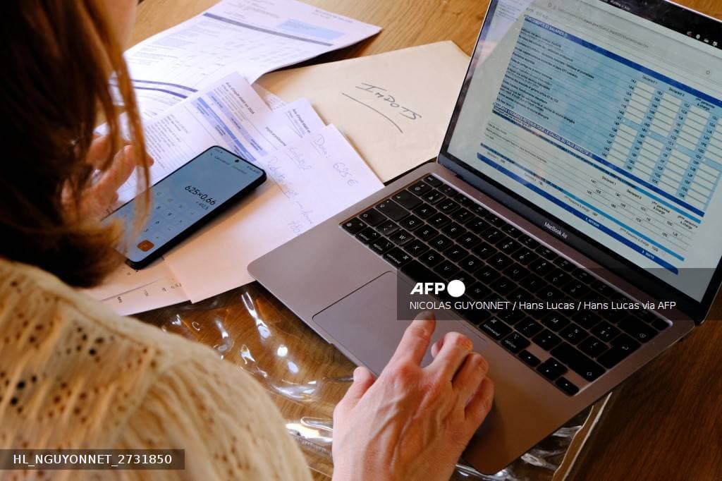 Contribuable remplissant sa declaration d'impots sur un ordinateur portable avec une calculatrice