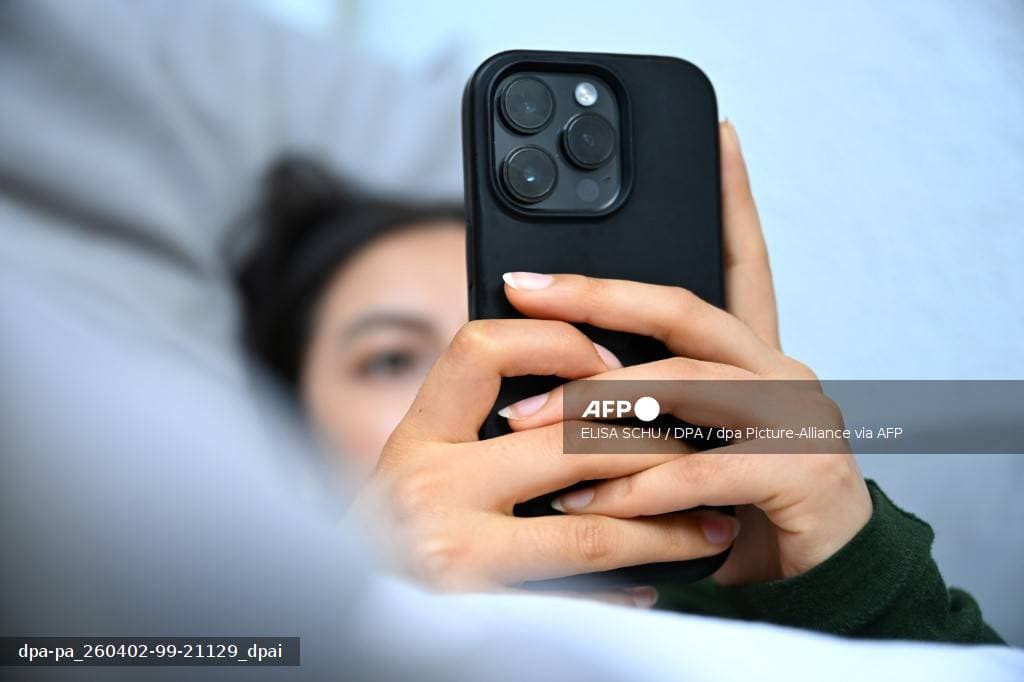 Jeune femme consultant son telephone dans son lit, illustrant le doomscrolling et l anxiete de guerre