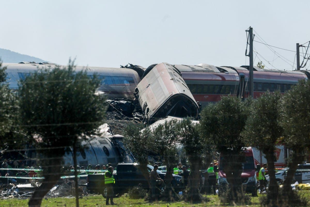 Des voitures de train déraillées et enchevêtrées, avec des secouristes et des véhicules de secours au premier plan