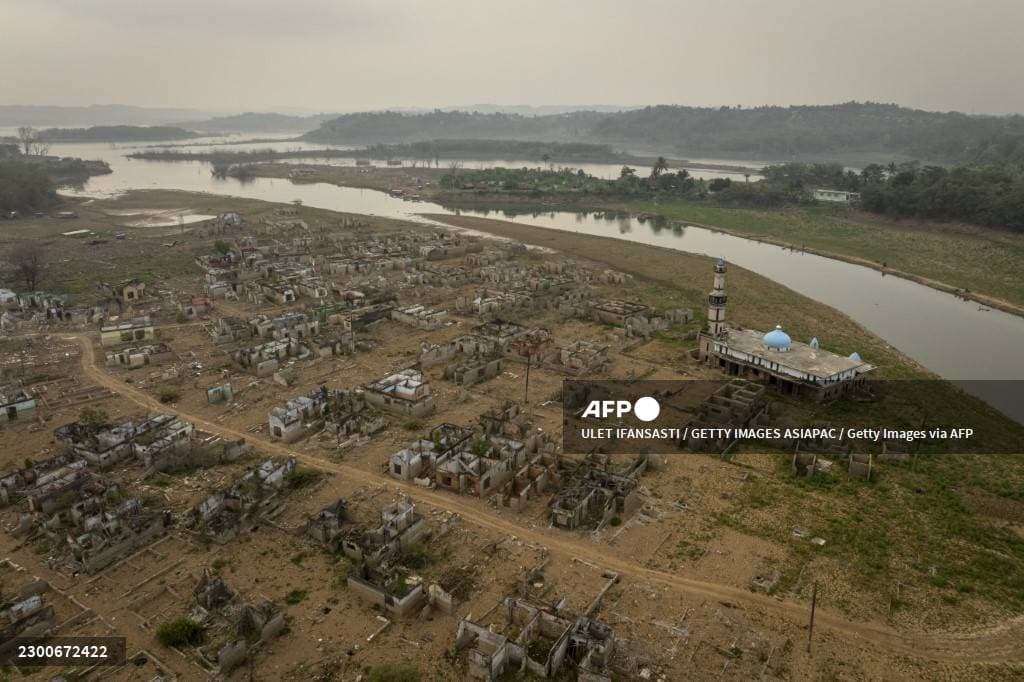 Vue aérienne de maisons en ruine et d'une mosquée sur le fond asséché d'un réservoir, en Indonésie