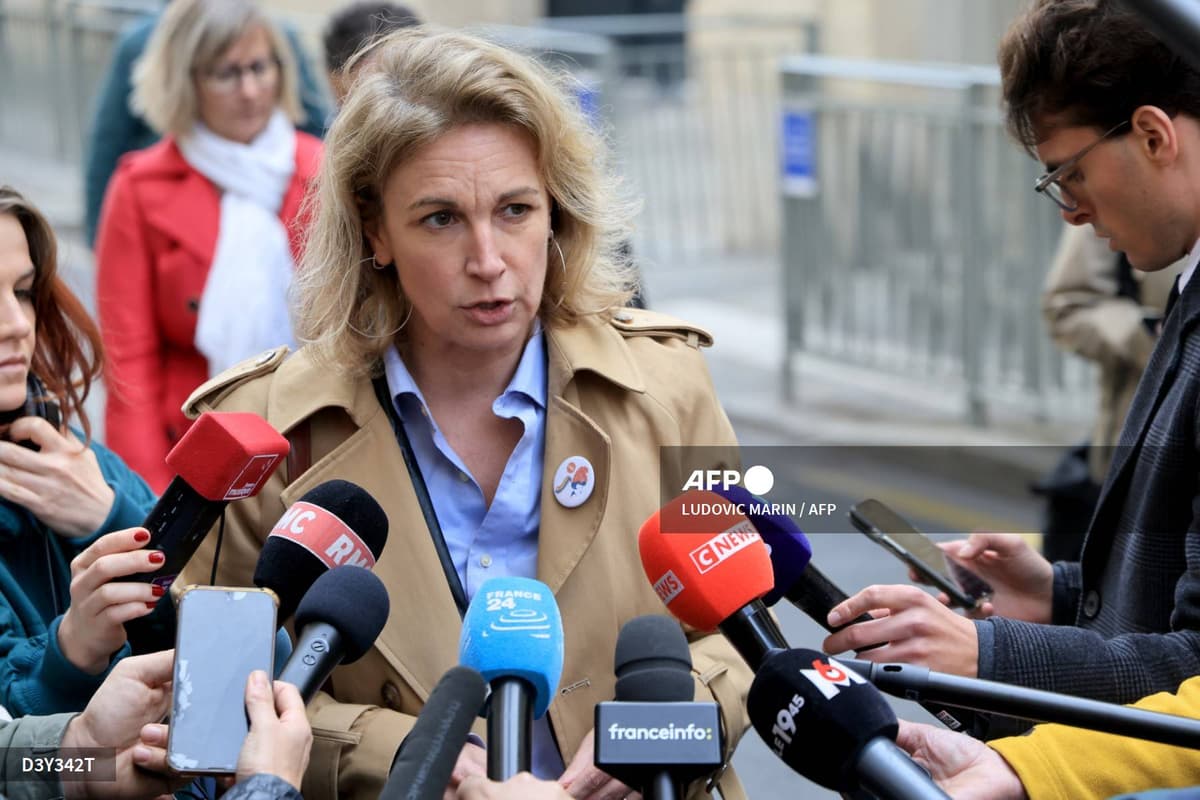 Marylise Léon, en trench beige, répond aux journalistes qui lui tendent des micros