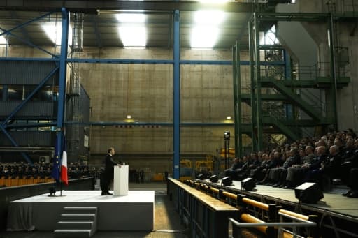 Emmanuel Macron au pupitre, dans un vaste hall industriel, devant des rangées de personnes assises