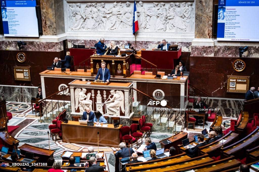L'hémicycle de l'Assemblée nationale, un orateur à la tribune, les écrans annonçant le débat sur les finances locales