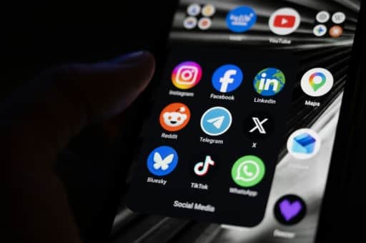Une main tient un téléphone dont l'écran affiche un dossier d'applications