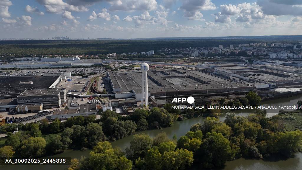 Vue aérienne de l'usine Stellantis de Poissy en Yvelines avec la Seine en arrière-plan, sa tour bleue emblématique et la Défense visible au loin, dernière usine d'assemblage automobile d'Île-de-France